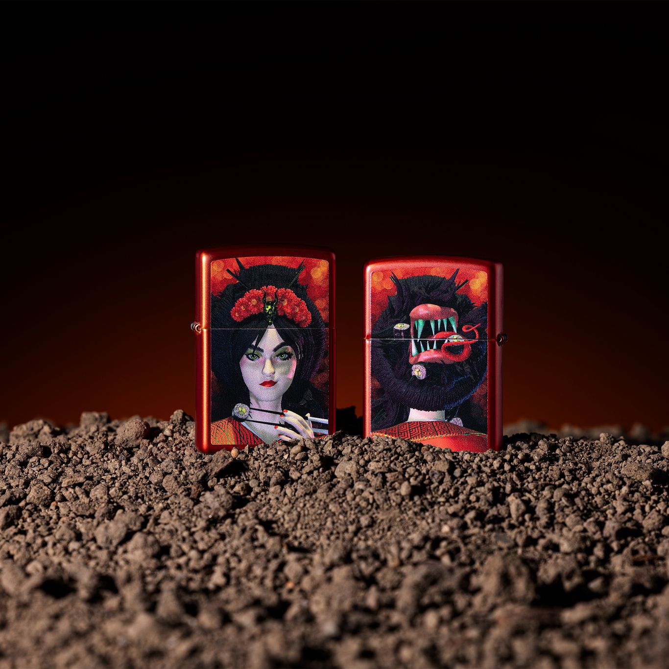Lifestyle image of two Zippo Dinner for Two Design Metallic Red Windproof Lighters; one showing the front of the lighter and the other showing the back of the lighter, both standing in dirt with a black and orange ombre background. 

