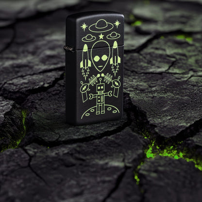 Lifestyle image of Zippo Alien Invasion Design SlimÂ® Black Matte Windproof Lighter standing on blacktop with green glowing cracks.